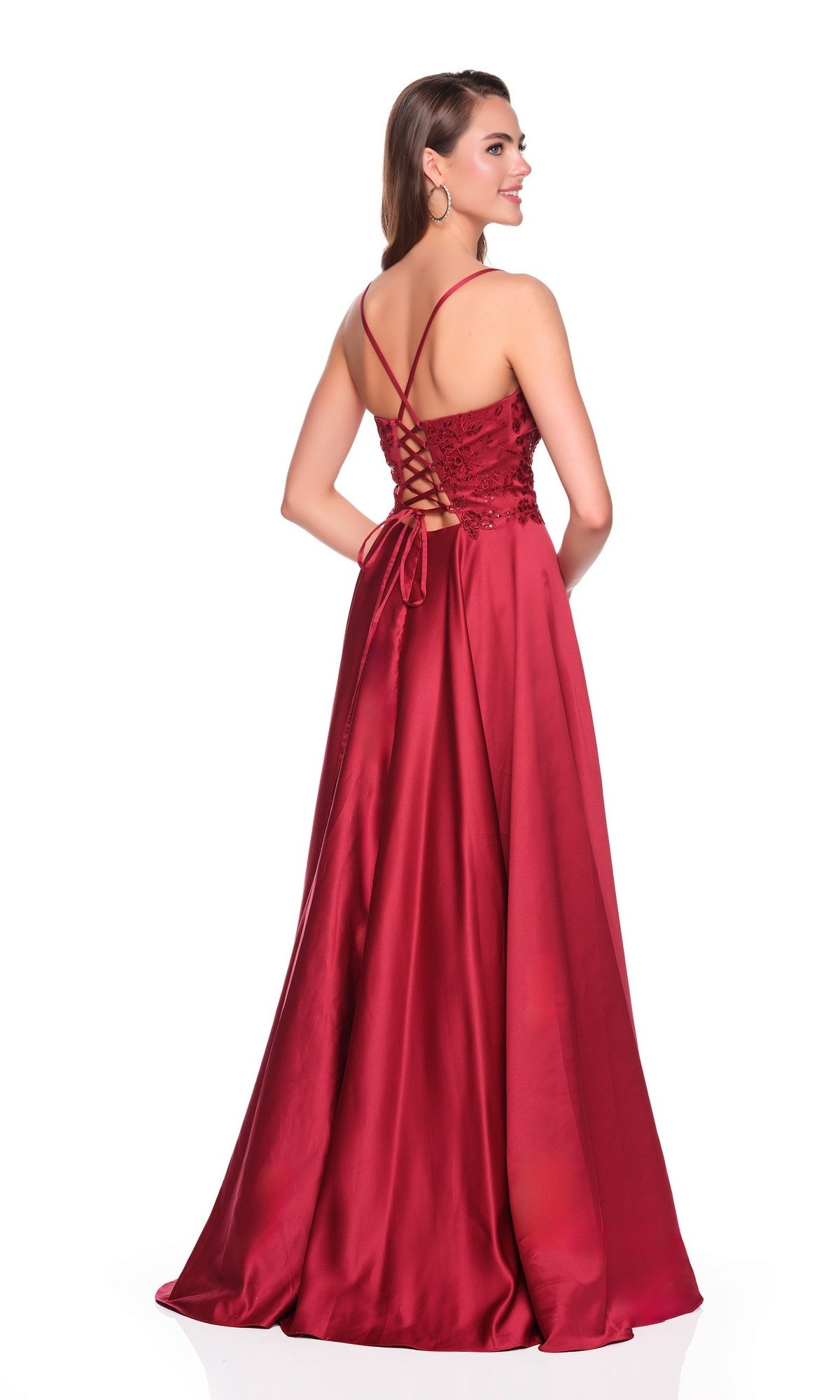A woman wears the Dave and Johnny 12873 Long Prom Dress—a sleeveless burgundy gown with thin straps and lace-up corset back—standing and looking over her shoulder.